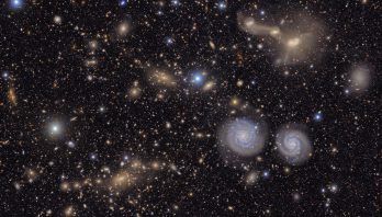 Many stars and galaxies including two spiral galaxies and three merging galaxies.