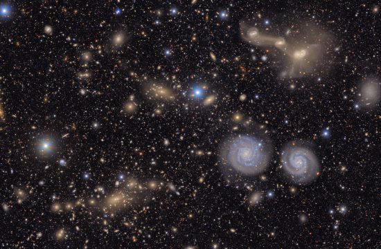 Many stars and galaxies including two spiral galaxies and three merging galaxies.
